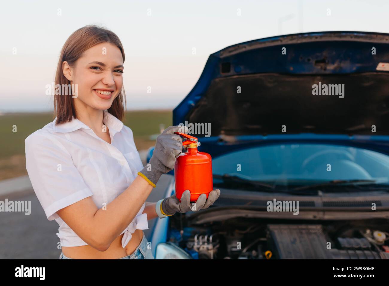 Young beautiful and hot woman driver holds a fire extinguisher in her hands, safety rules while traveling Stock Photo