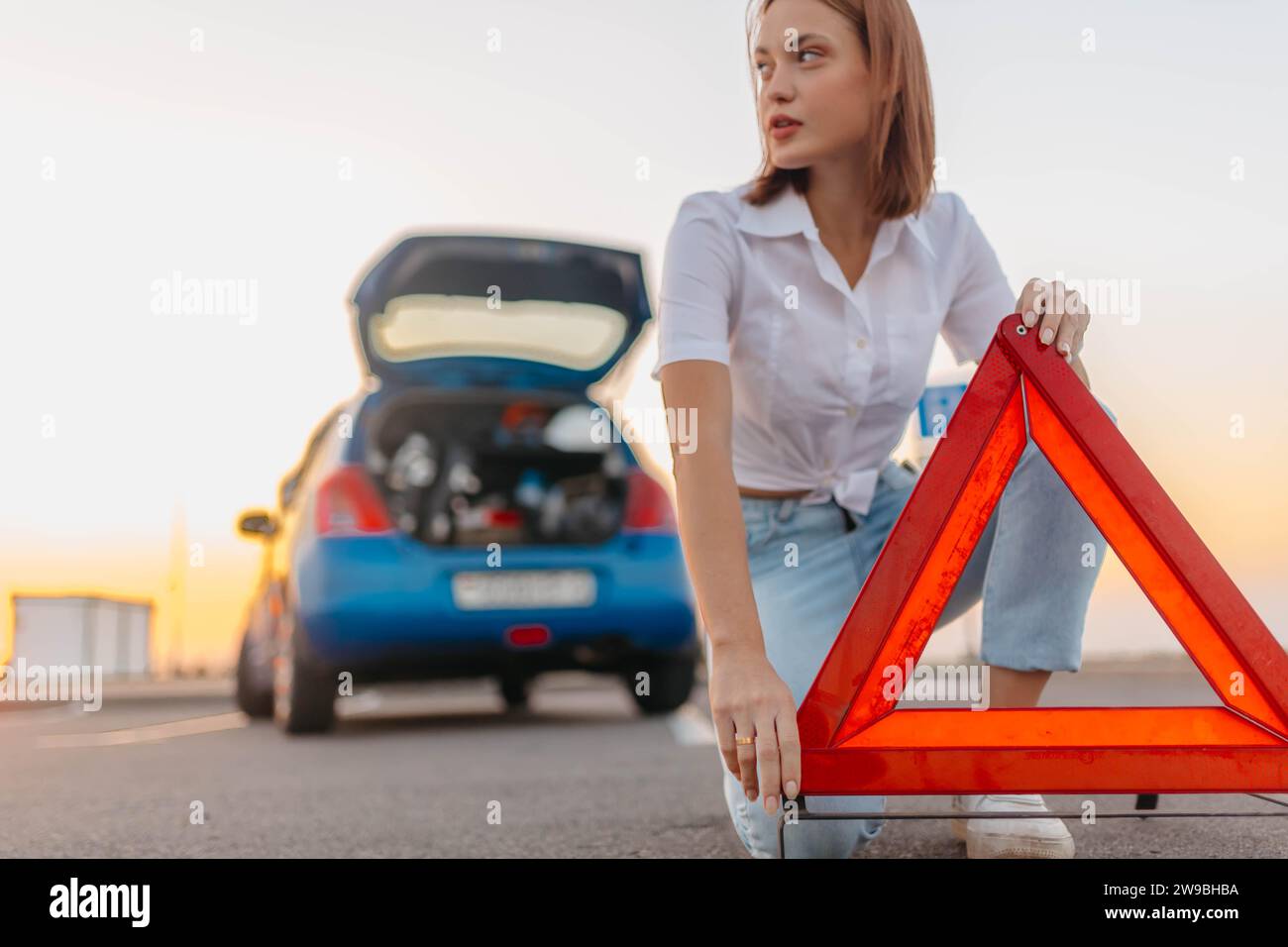 Young beautiful and hot woman driver installs a warning triangle ...