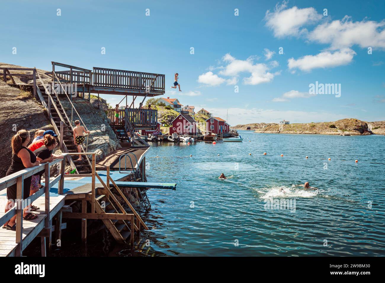 Children and teenagers jump from the high diving platform into the sea in the Stocken archipelago on the west coast of Sweden Stock Photo