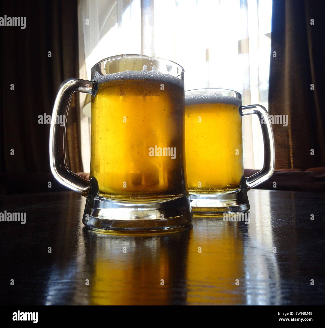 Full glasses of light beer on the wooden table at restaurant Stock Photo