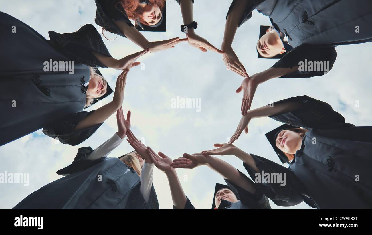 College graduates make a circle of their hands. Stock Photo