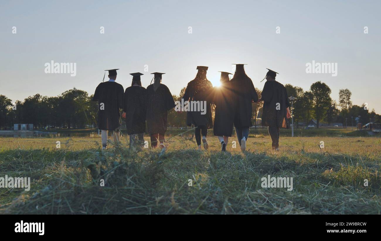 Graduate students walking through an evening meadow at sunset. Stock Photo