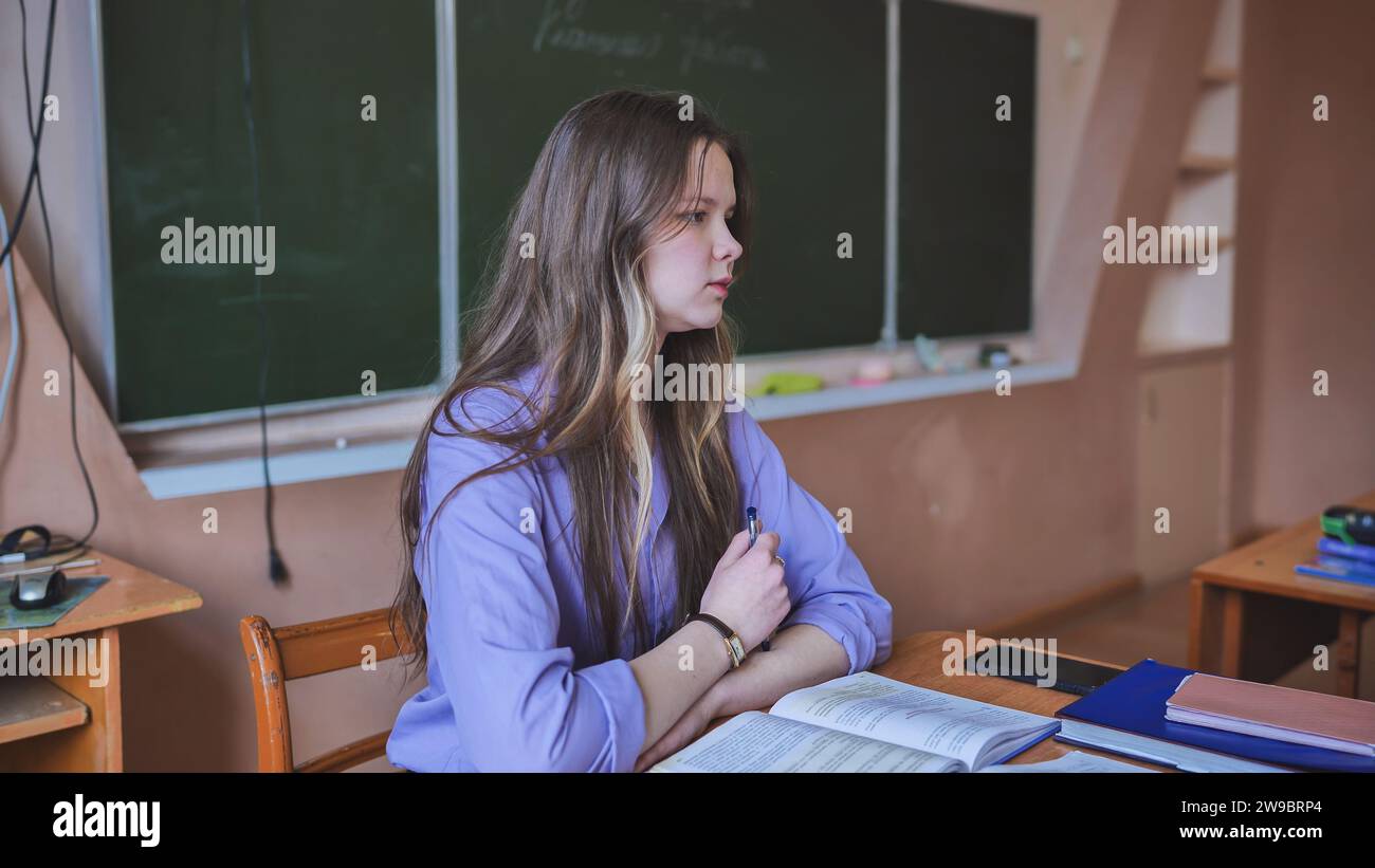 A schoolgirl in the role of a teacher sits at her desk Stock Photo - Alamy