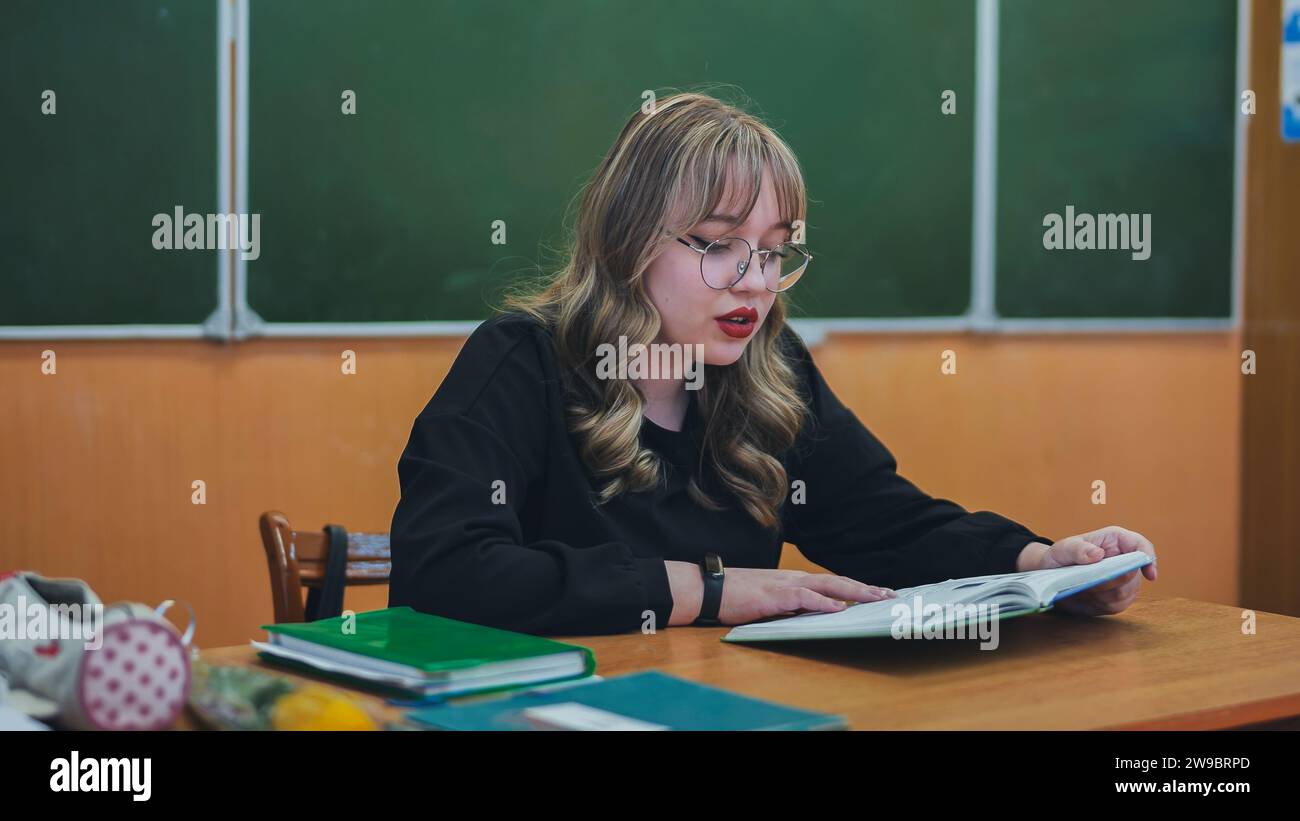 A schoolgirl in the role of a teacher sits at her desk Stock Photo - Alamy