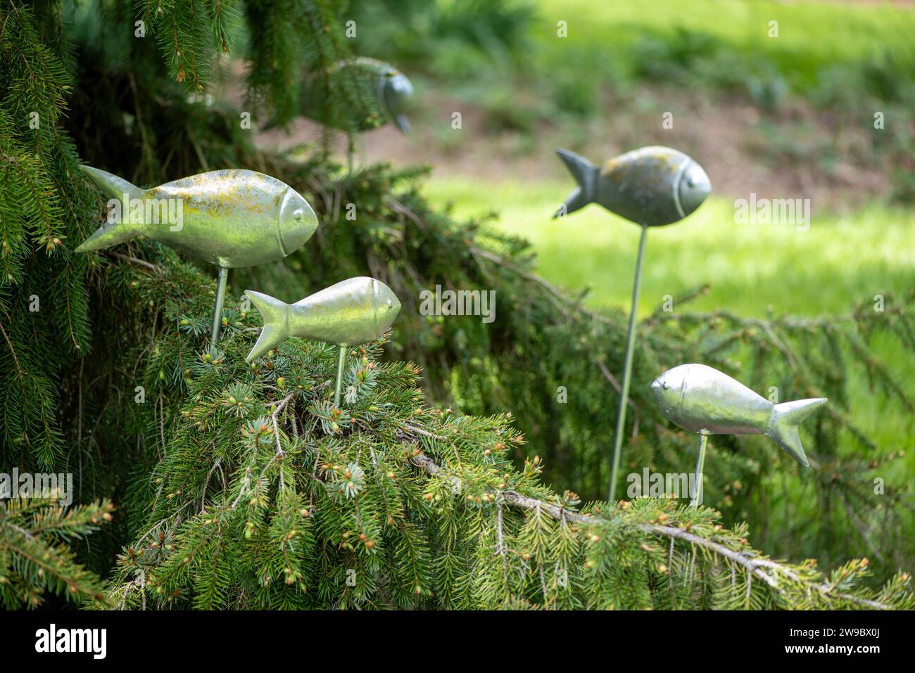 whimsy metal fish statues swimming in garden display Stock Photo