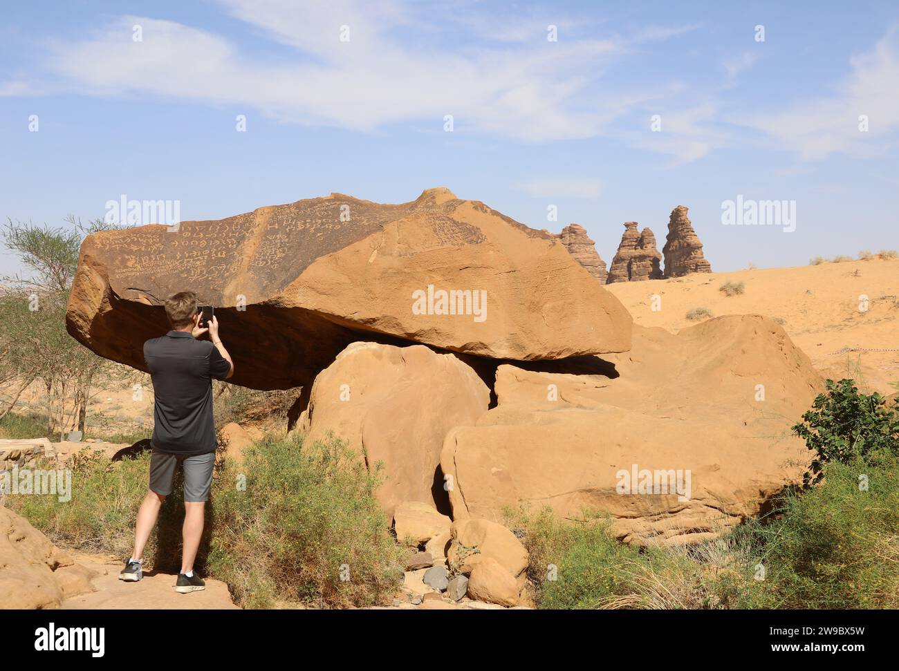 Tourist photographing the ancient inscriptions at Jabal Ikmah on a tour ...