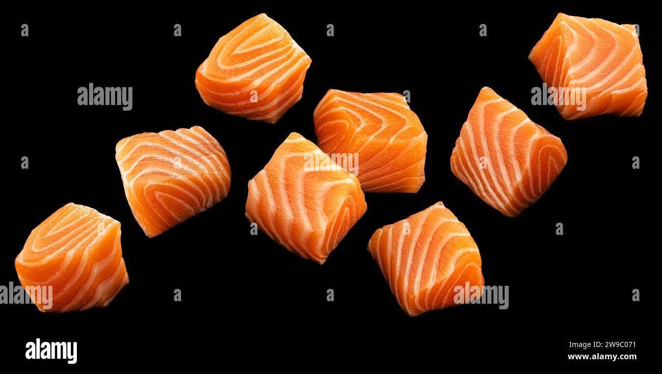 Falling salmon cubes on black background Stock Photo