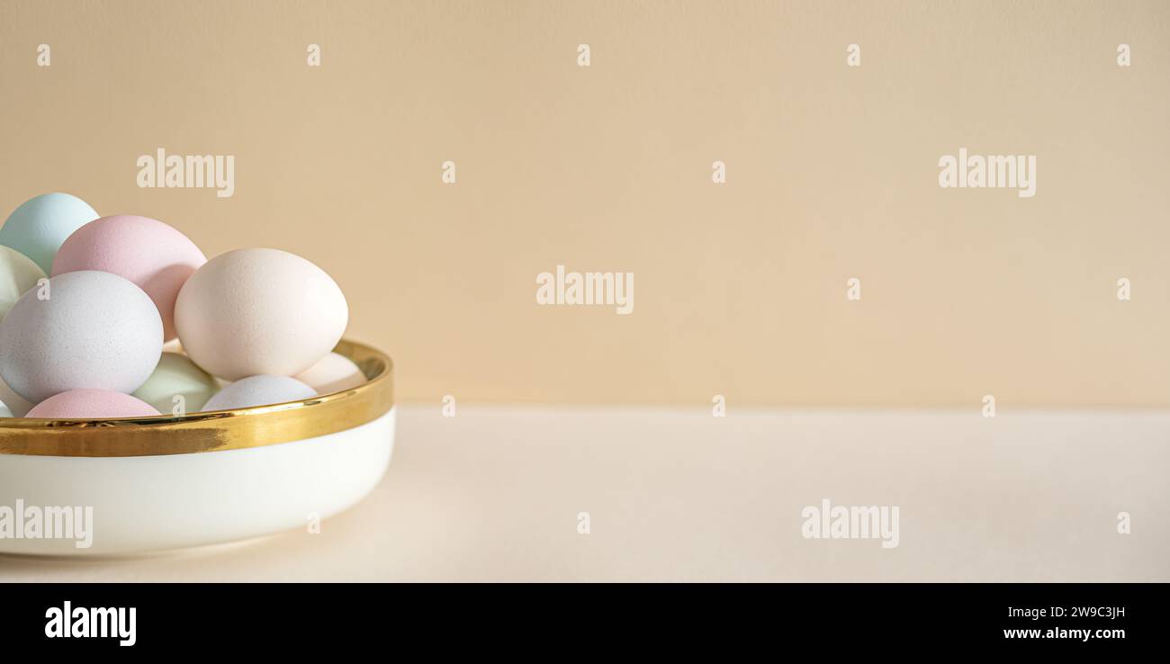 Pastel colored Easter eggs in white bowl on a table Stock Photo