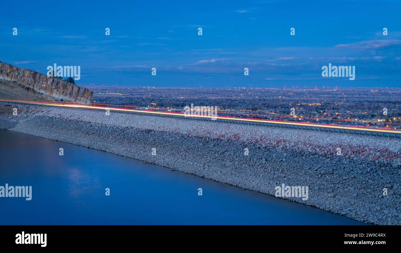 dusk over a dam in Horsetooth Reservoir at a foothills of Rocky Mountains in a fall or winter dusk scenery with lights of highway traffic and distand Stock Photo