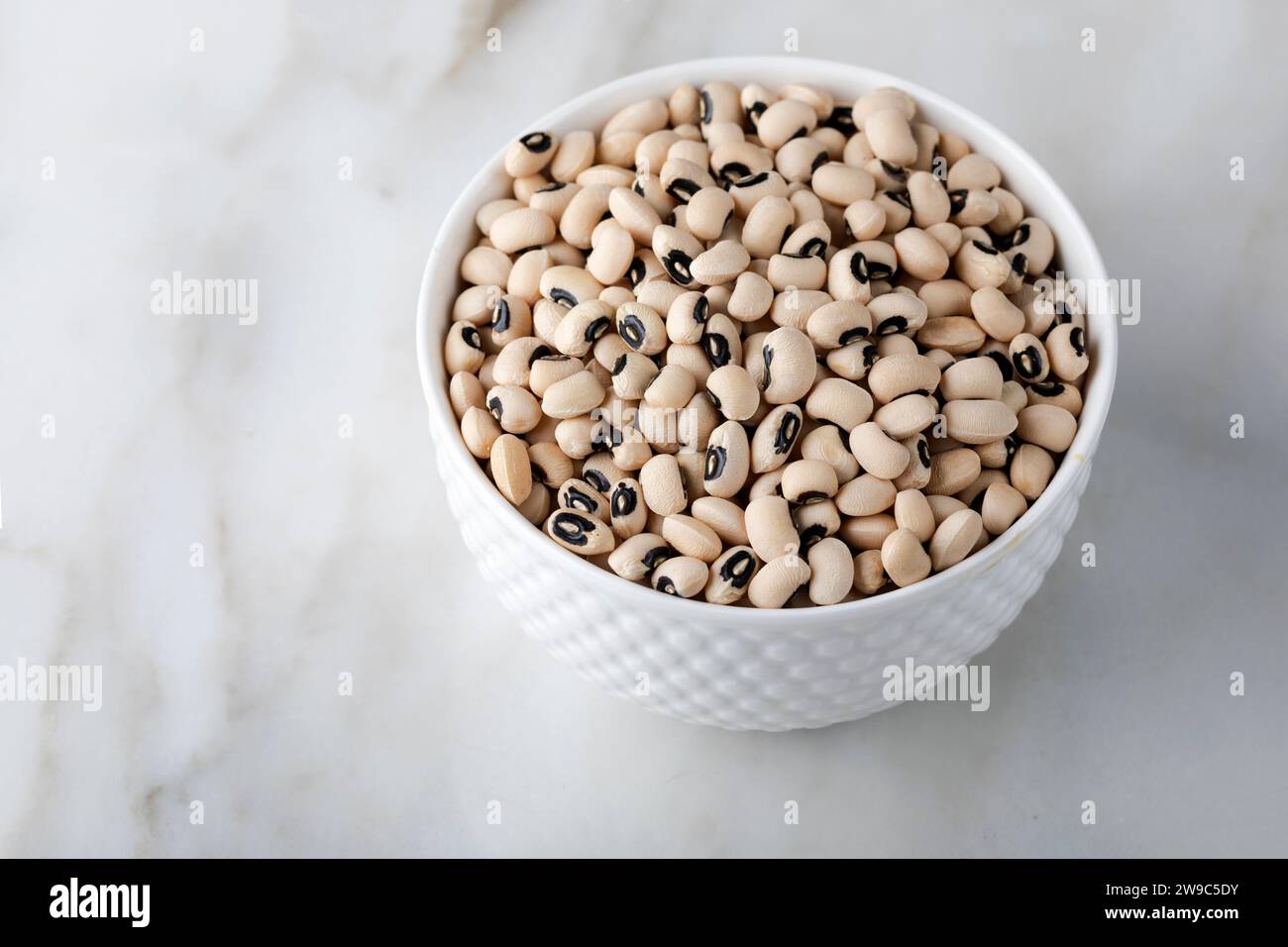 Black eye peas in a white bowl on a white marble background. Stock Photo