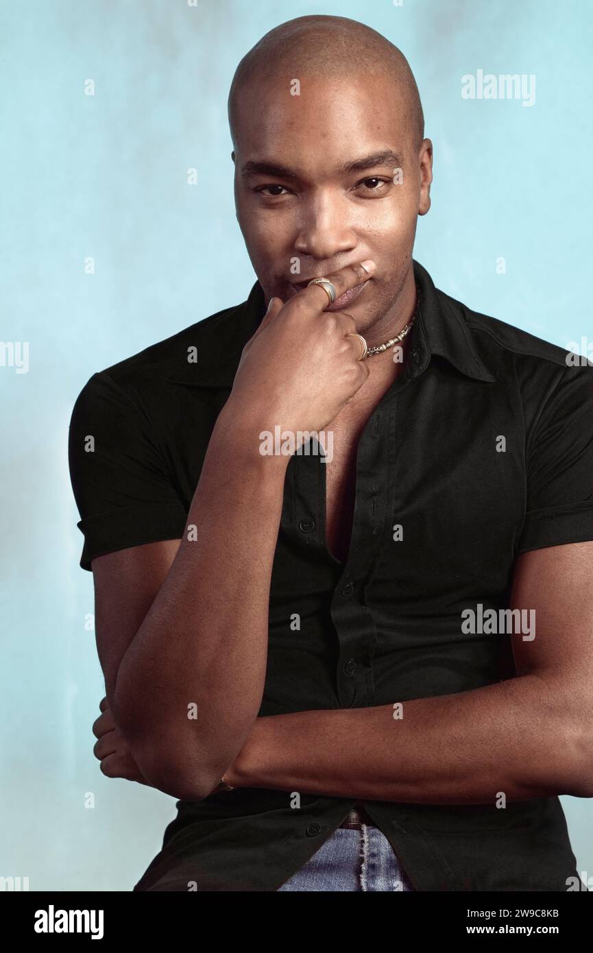 Portrait of an African American man with a shaved head wearing a black shirt on a plain Studio background Stock Photo
