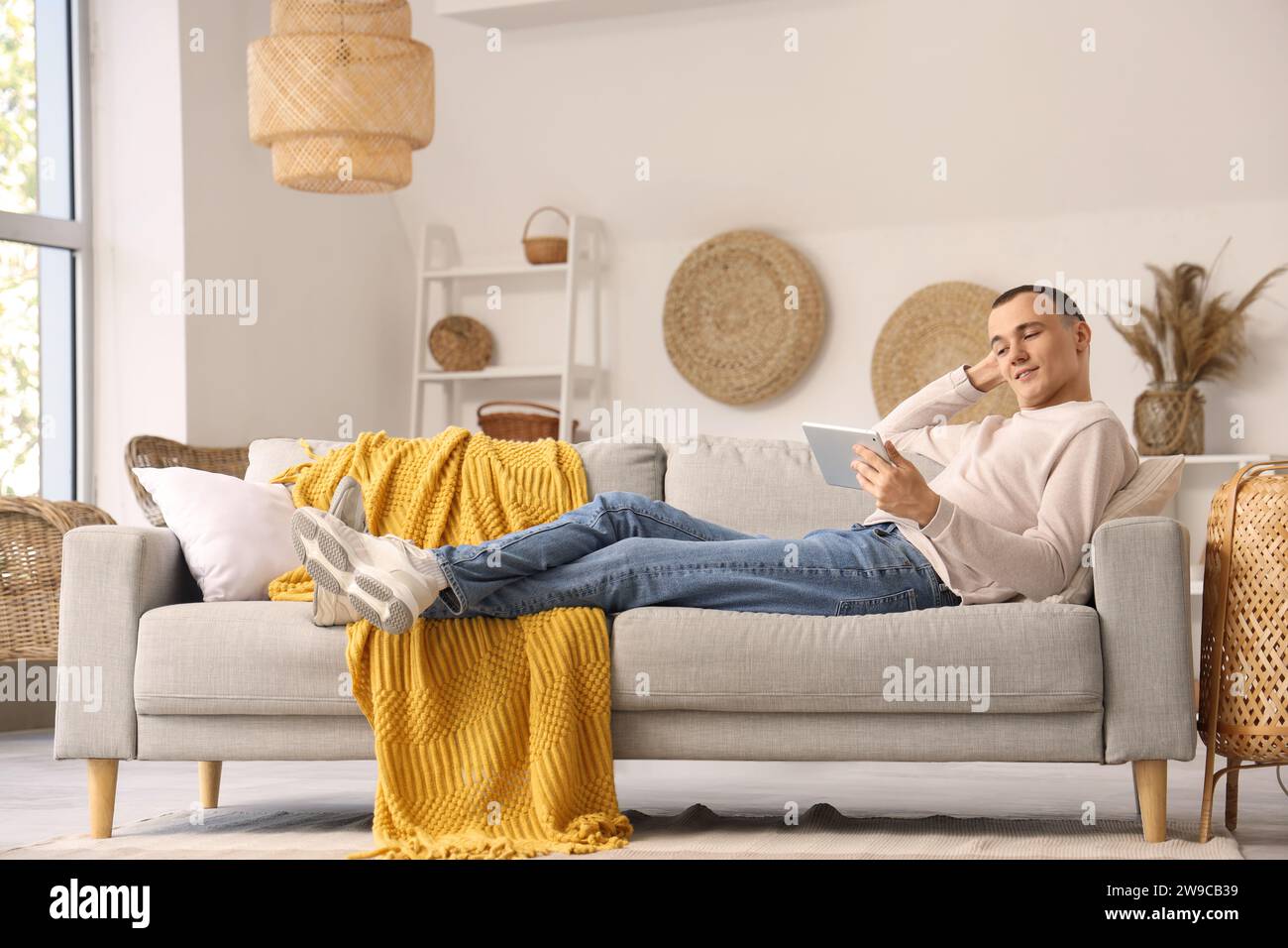 Young man using tablet computer on sofa at home Stock Photo