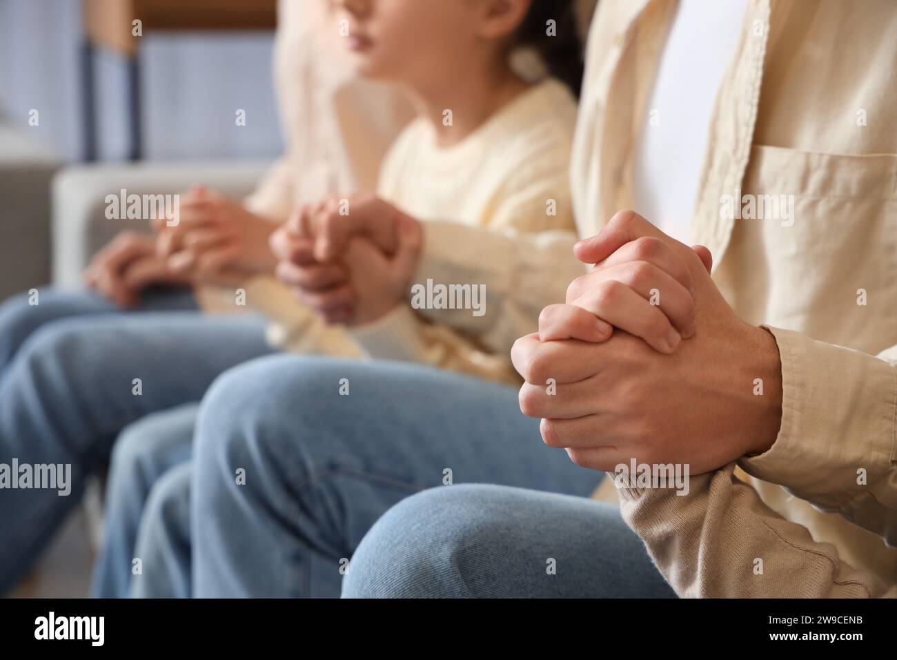 Family praying on sofa at home, closeup Stock Photo