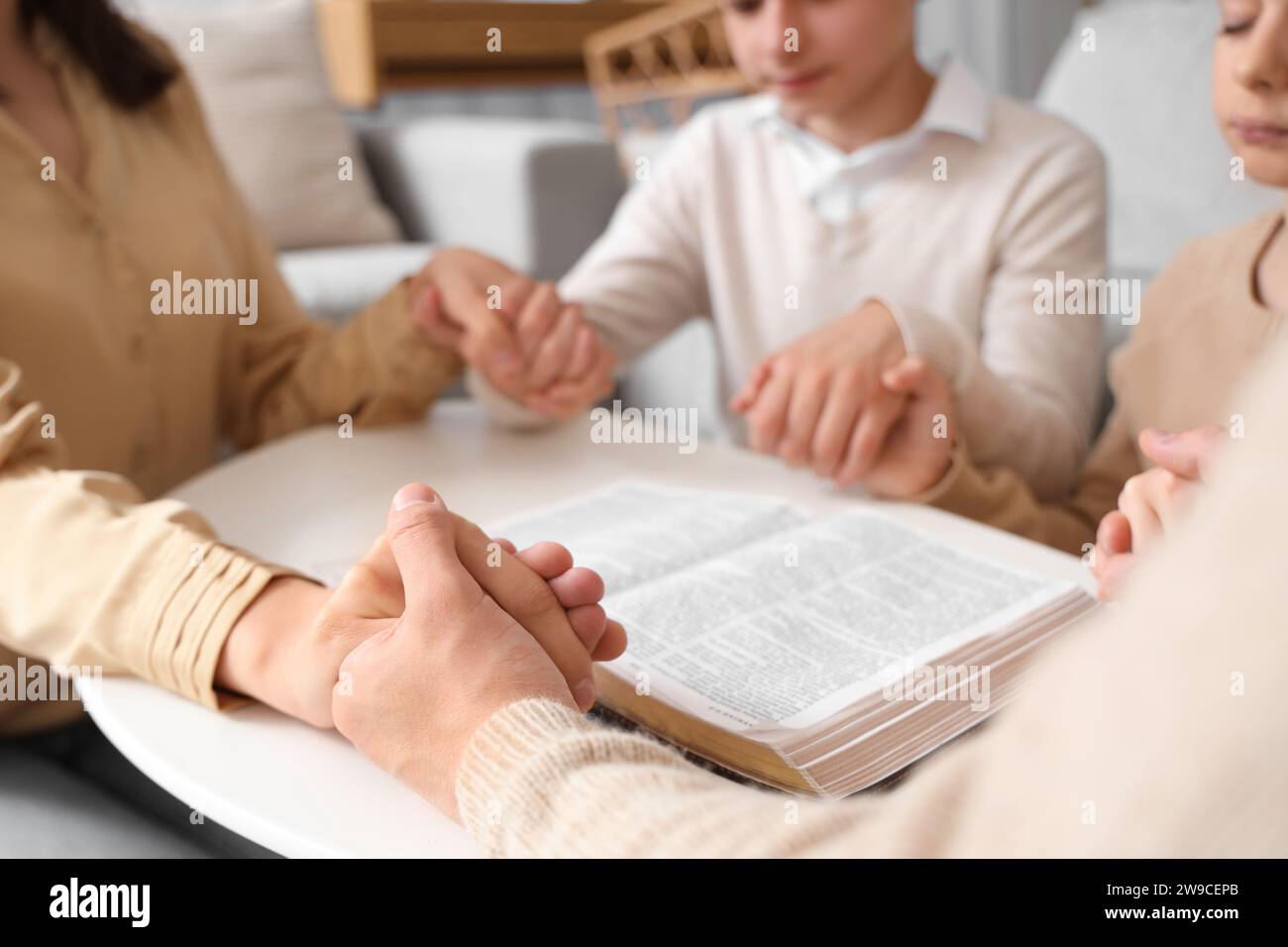 Family praying with Holy Bible on table at home, closeup Stock Photo