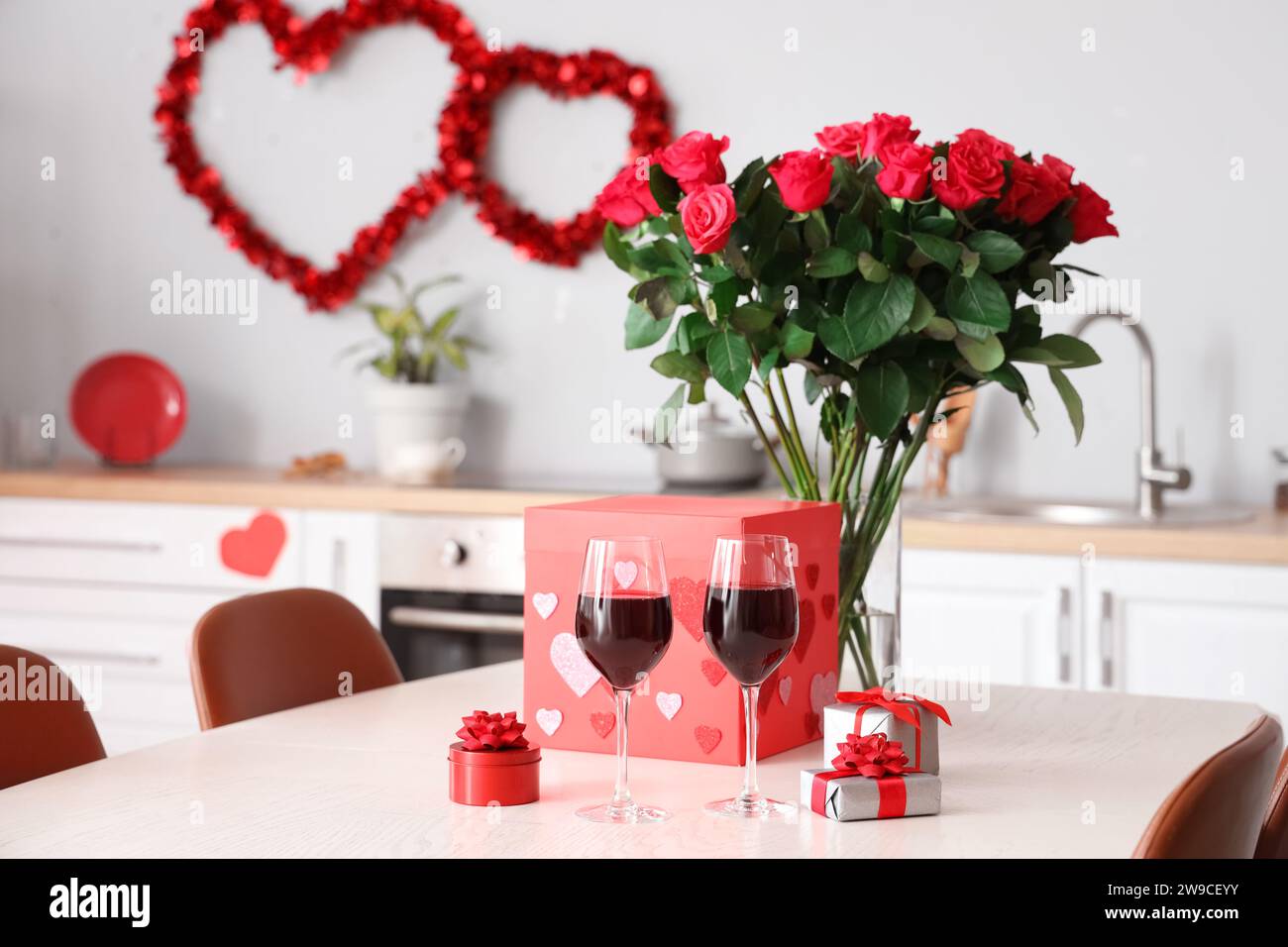 Dining table with bouquet of roses, wine glasses and gift boxes in