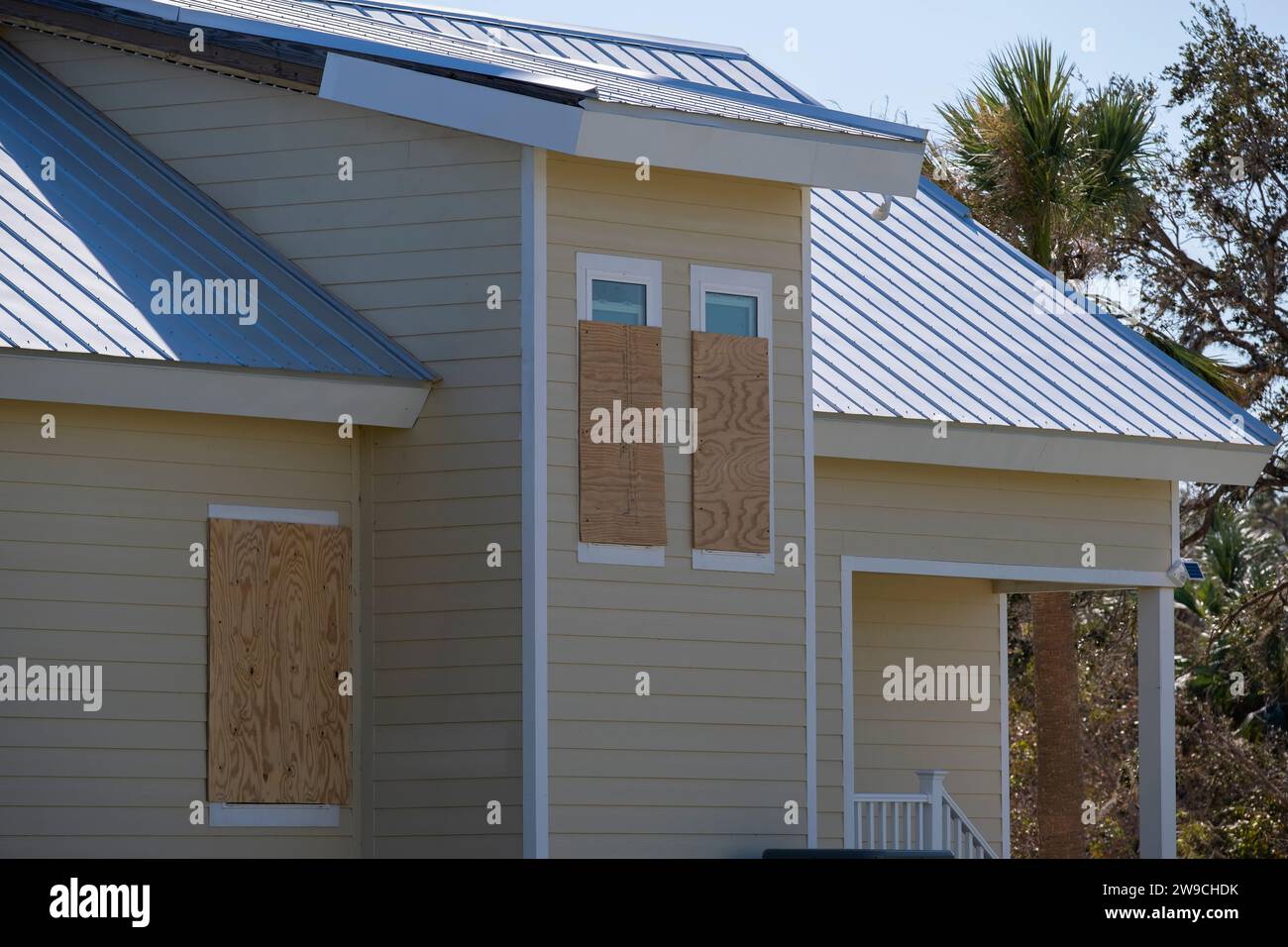 Plywood mounted as storm shutters for hurricane protection of house windows. Protective measures before natural disaster in Florida. Stock Photo