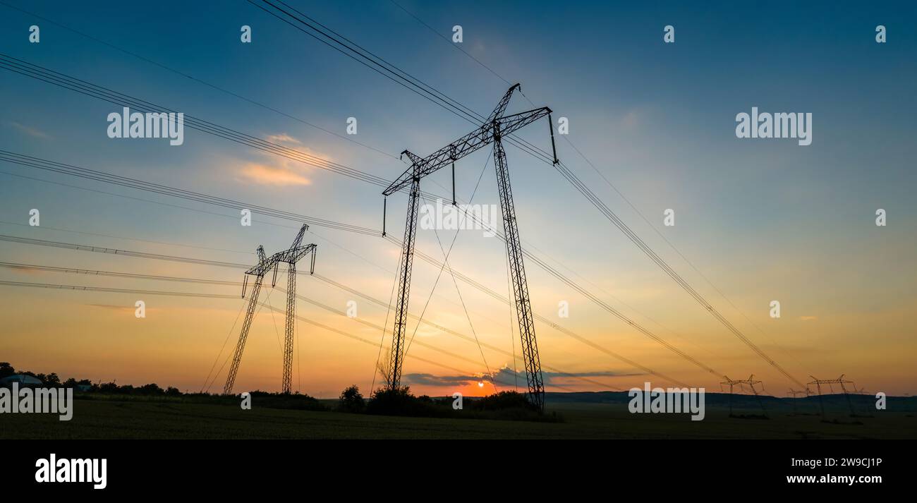 Dark silhouette of high voltage towers with electric power lines at ...