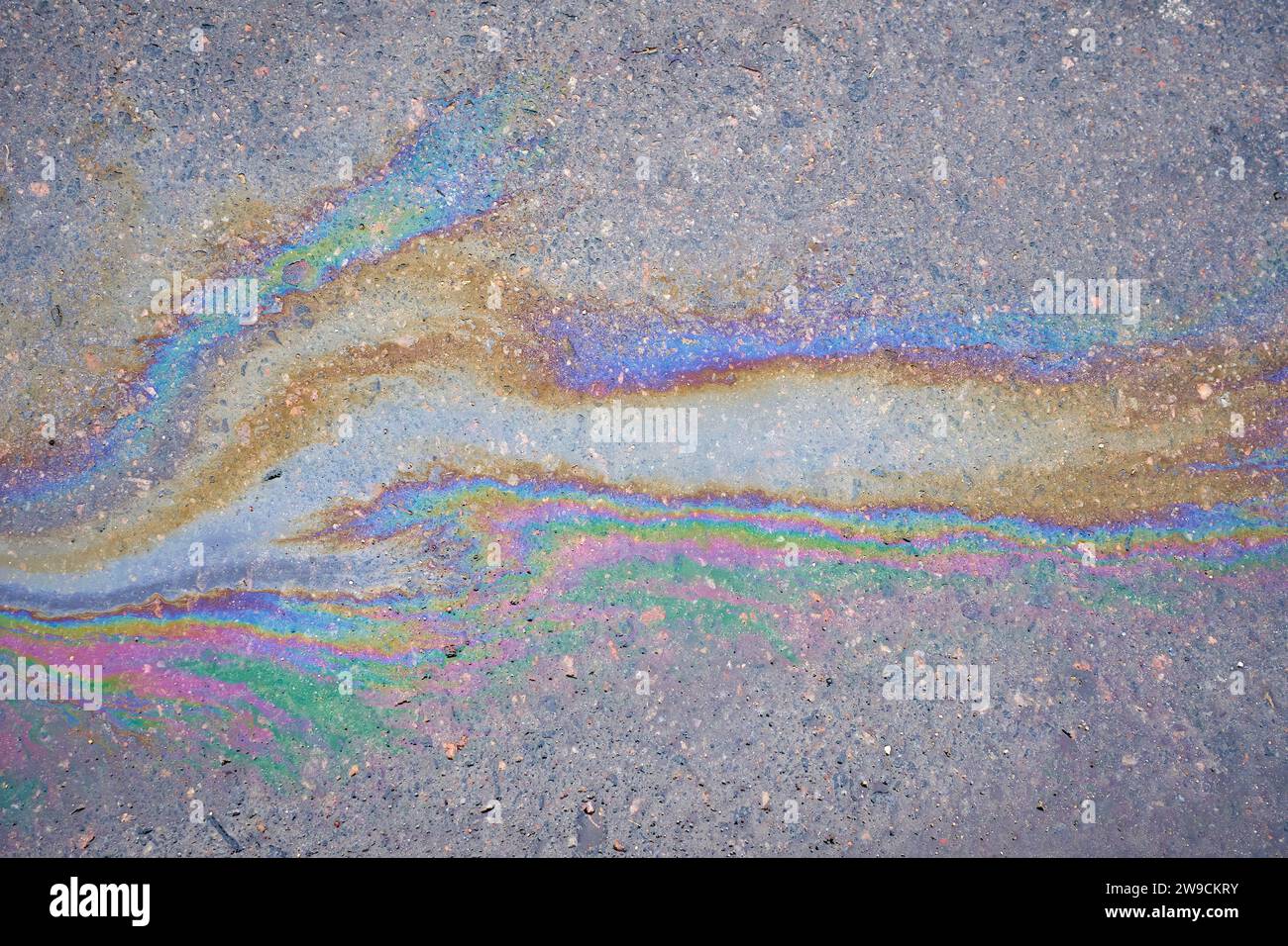 Multicolored poisonous spots of spilled gasoline on wet pavement