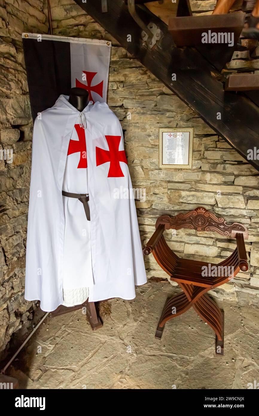 A Knights Templar robe and flag displayed under the stairs in a corner of Vezio Castle in Perledo, Lombardy, Italy. Stock Photo