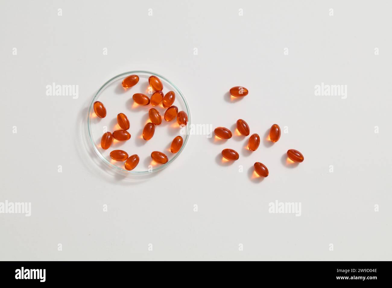 Orange fish oil capsules, adorned with petri dish, all placed on a