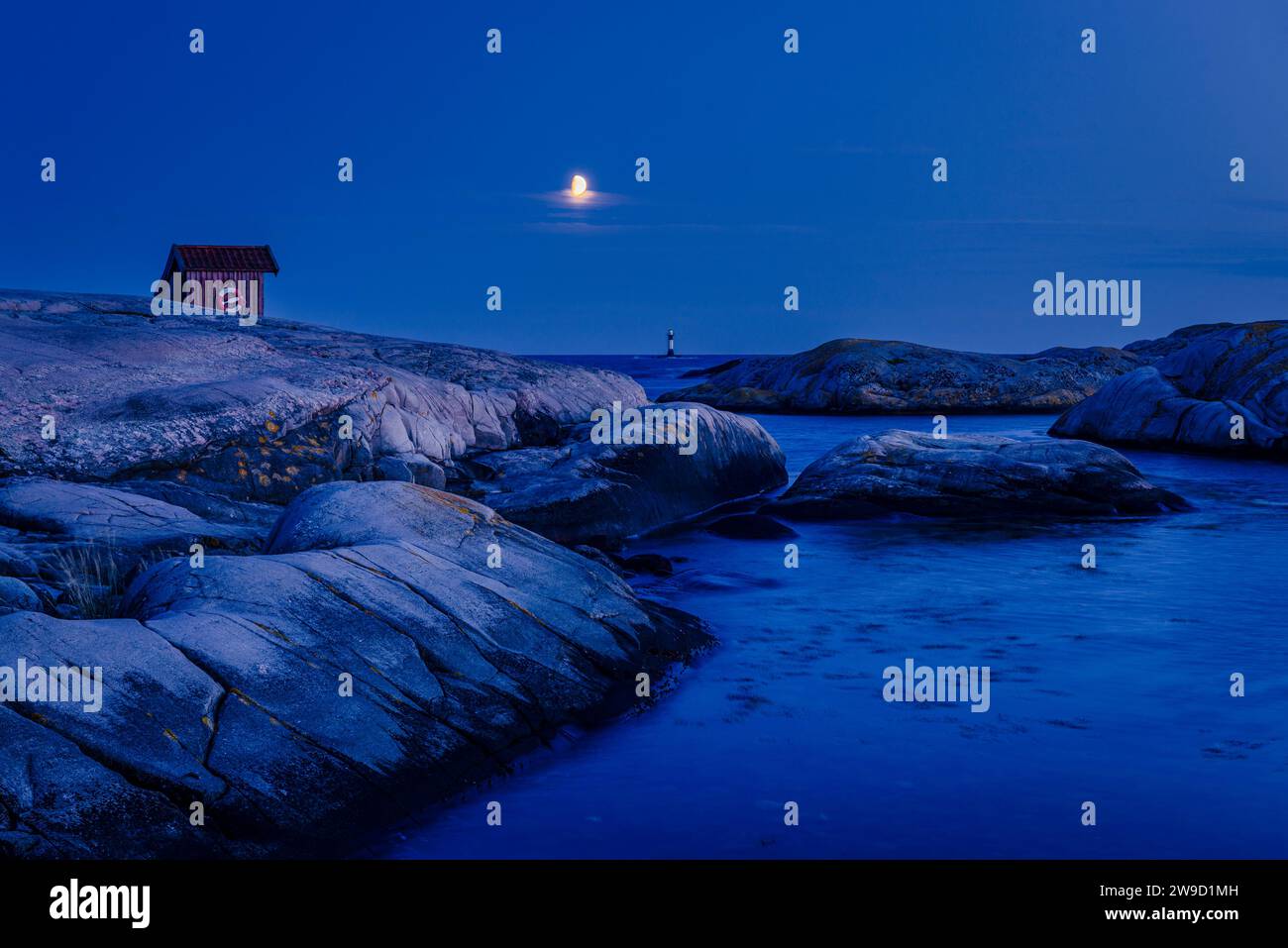 The moon above a wooden hut on rocks on the banks of the Skagerrak in the Tjurpannan nature reserve in the archipelago of the Swedish west coast Stock Photo