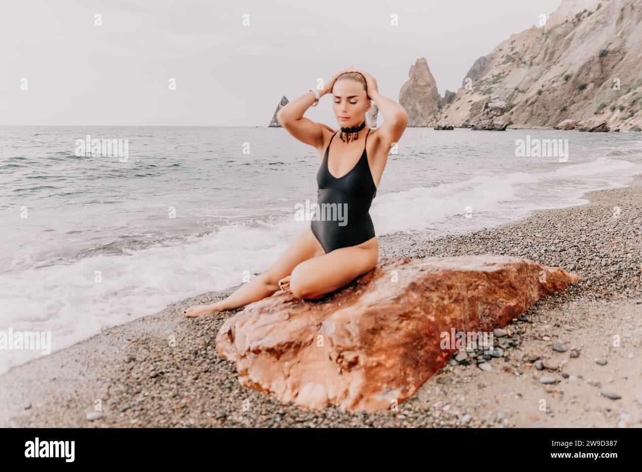 A beauty in a red swimsuit with long legs poses - Stock Photo