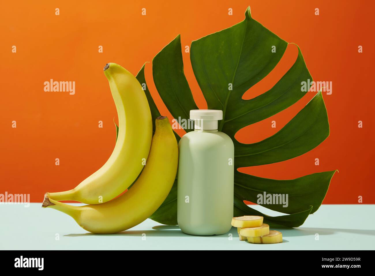 Green bottle unlabeled decorated with fresh bananas and green monstera