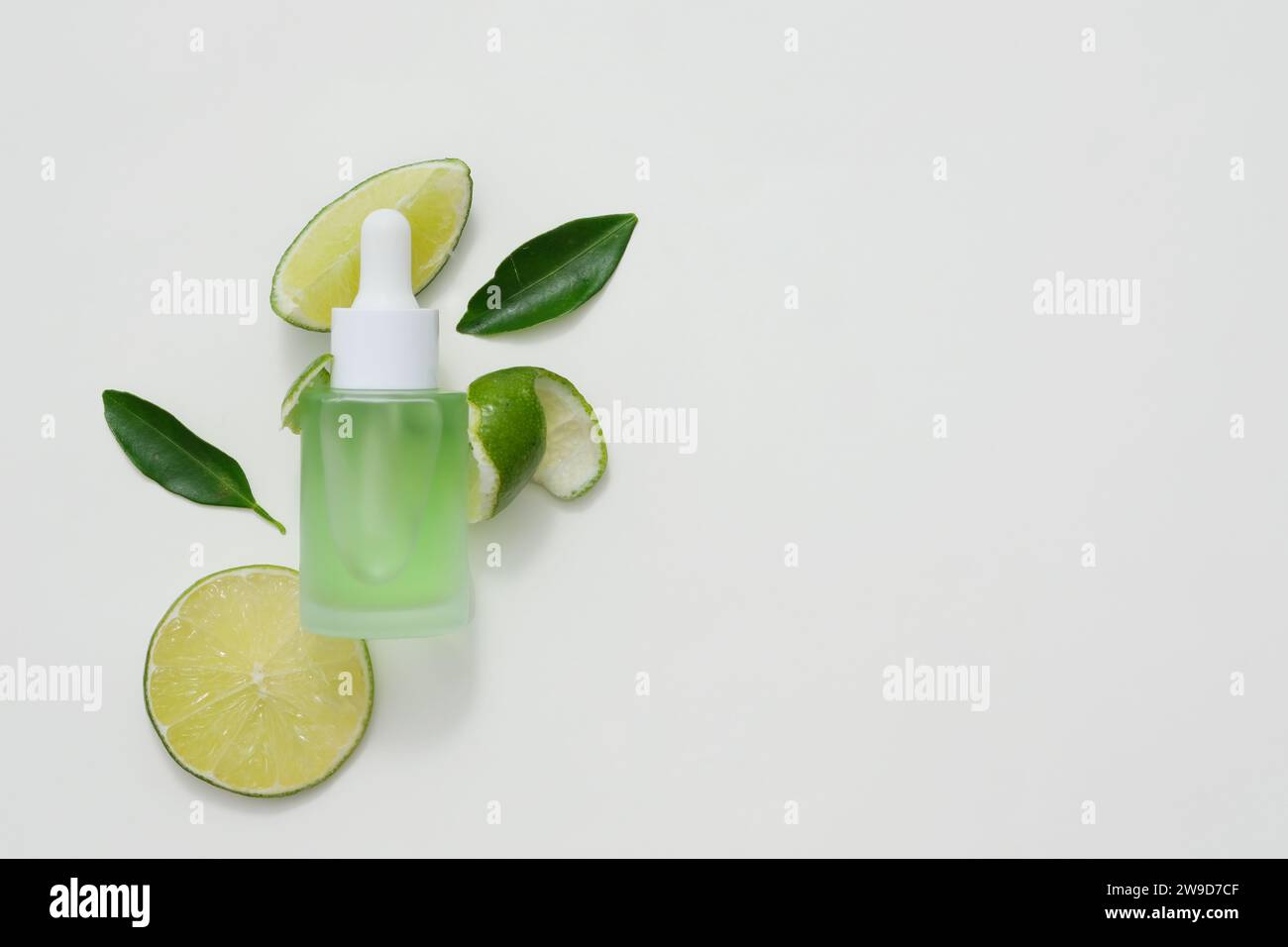 Background for the presentation of cosmetic products extracted from lime. A dropper bottle without label mockup for design. Space for text. Top view Stock Photo