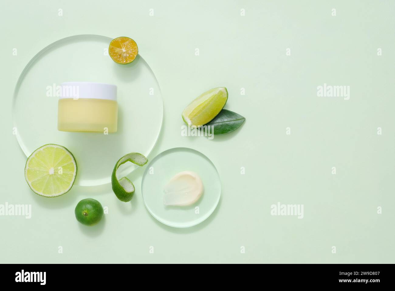 Beauty product packaging design templates based on lime. A yellow cream jar without label displayed on transparent podium for design. Space for text Stock Photo