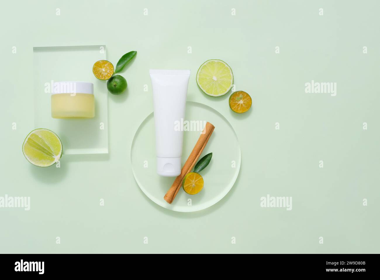 On the pastel background, set of cosmetic bottles displayed with slices of lime and kumquat, cinnamon stick decorated. Mock up for package design. Nat Stock Photo