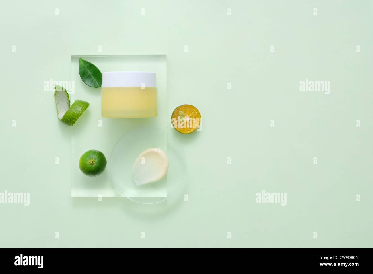 Mockup packaging, cosmetic jar unbranded for design is displayed on transparent podium with slices of kumquat. Concept for advertising natural cosmeti Stock Photo