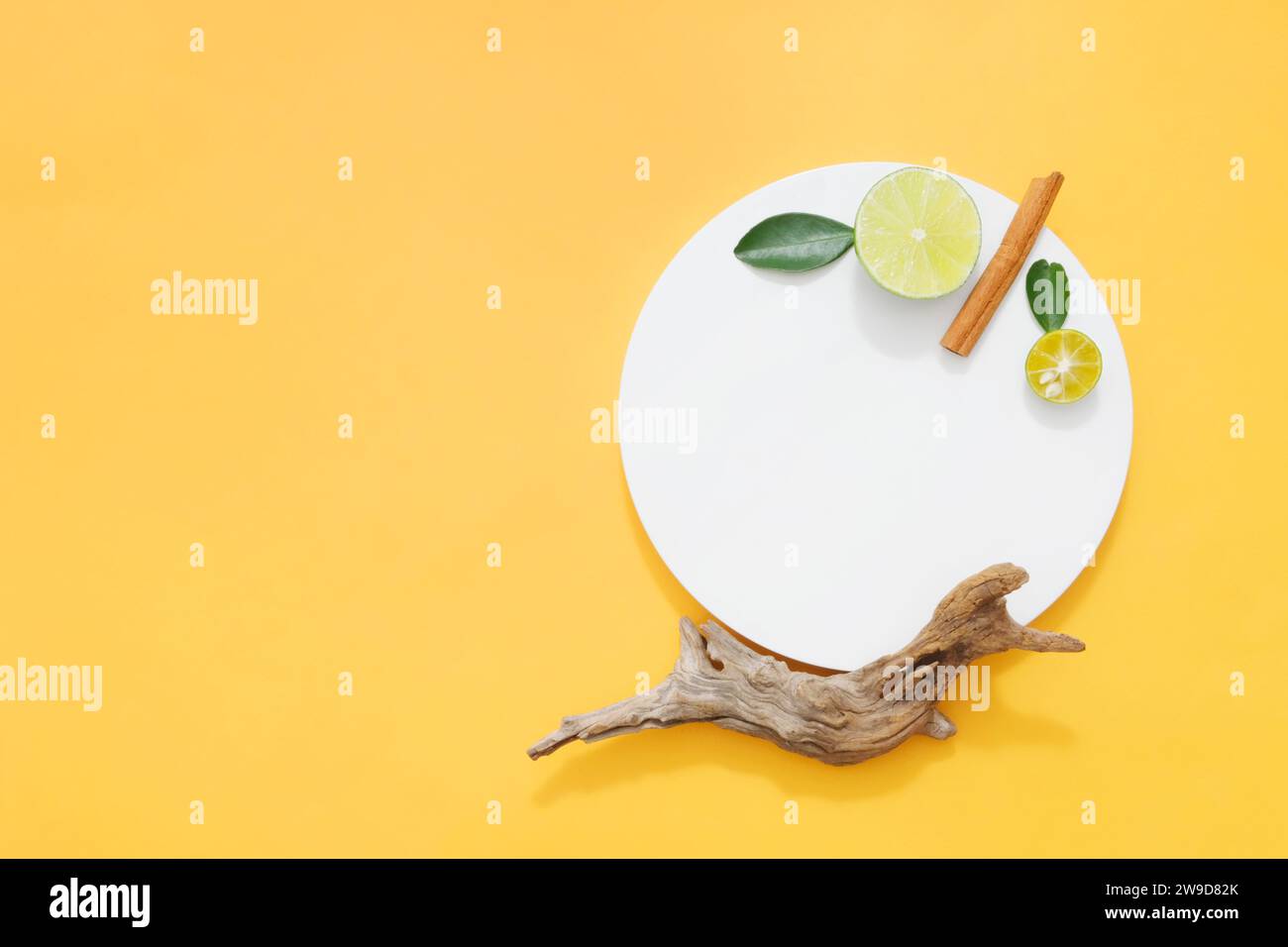 On a white round podium, slices of lime, kumquat and cinnamon are decorated. Blank space for display product. Top view, minimalist concept for adverti Stock Photo