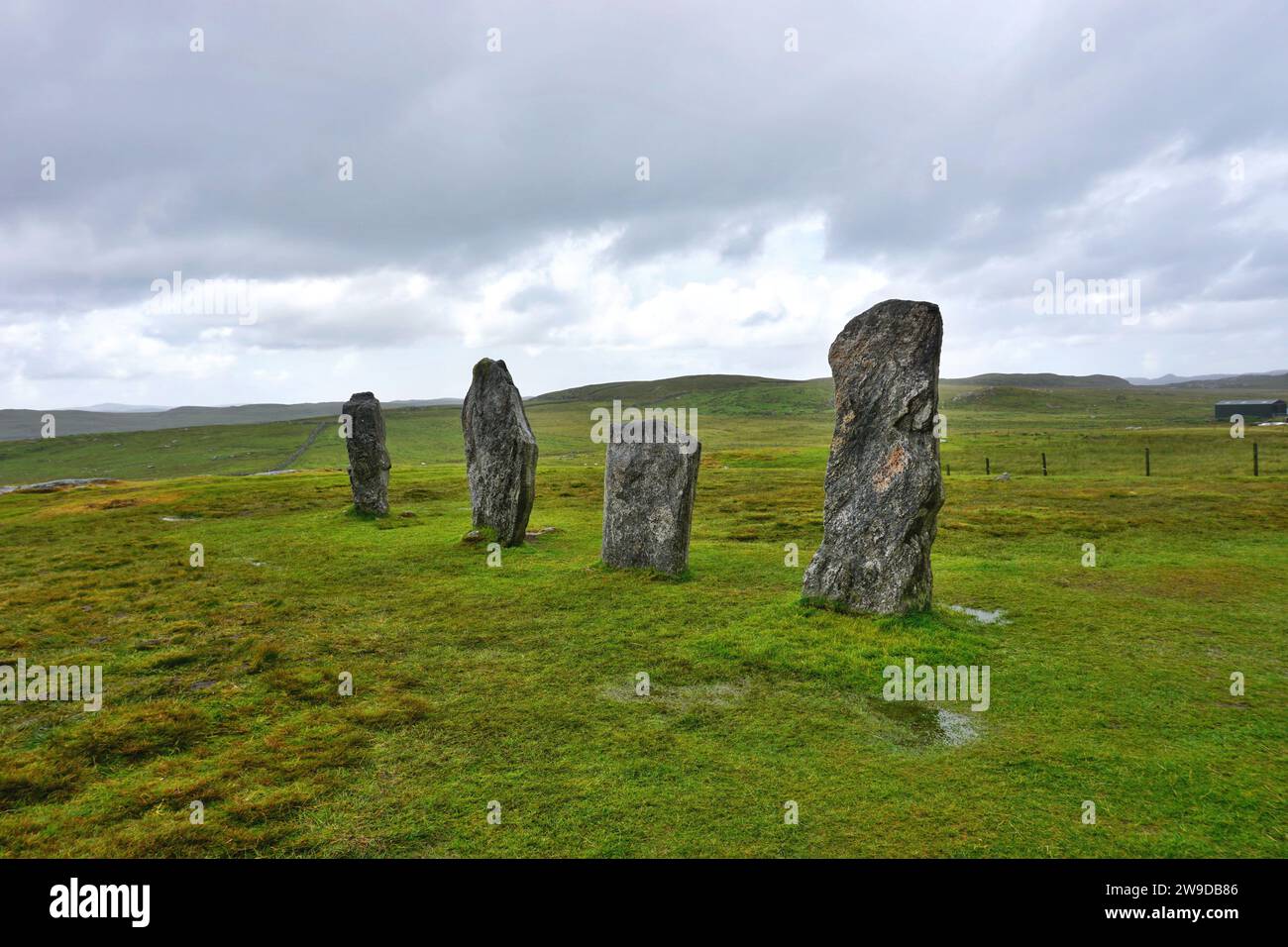 A quartet of ancient standing stones contrast with the bright green meadow at the Callanish Neolithic site in a remote corner of Lewis Island Scotland Stock Photo