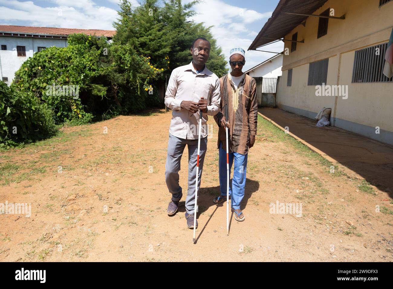 Two blind friends help each other with their white canes by walking toward the promenade. Stock Photo