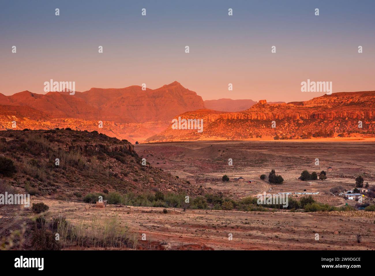 A few scattered huts and buildings against the backdrop of mountains in Lesotho, Africa Stock Photo