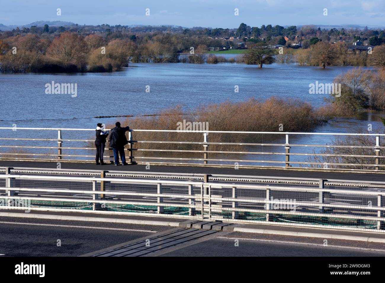 Couple watching flood waters from Carrington Bridge at the convergence of River Teme and River Severn with Lower Wick beyond, Worcester, UK Stock Photo