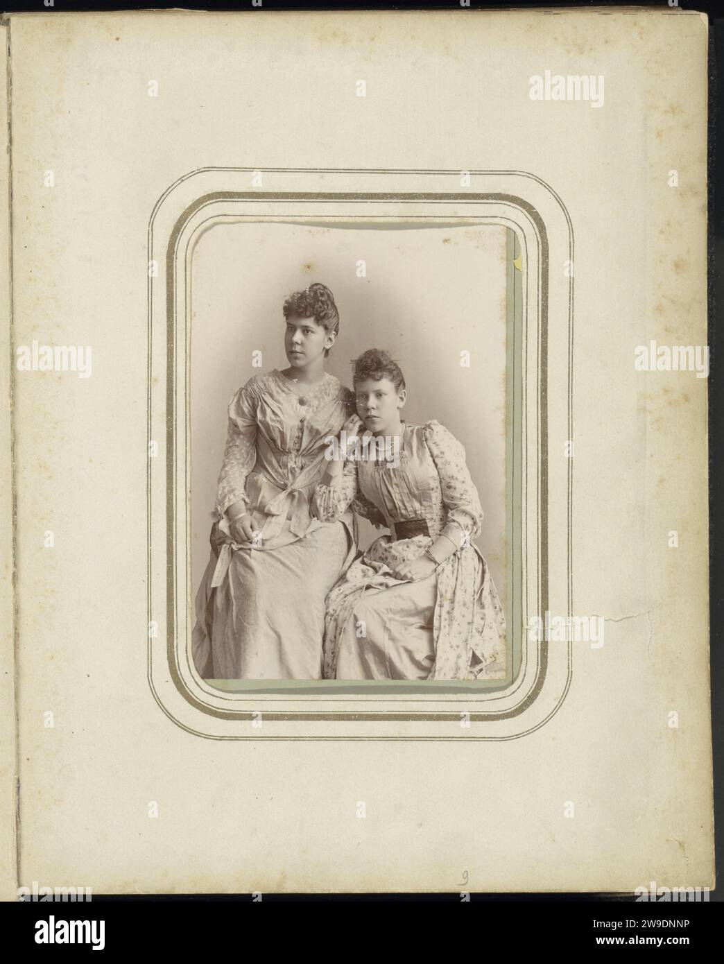 Portrait of two women in dresses, 1885 - 1924 cabinet photograph Part of Family Album of H.W.F. Ligtenberg and L.M. Swart with 149 photos and cartes-de-visiting. Netherlands cardboard. photographic support  historical persons. family, relationship, descent. dress, gown. styles of hairdress - AA -  women Netherlands. Batavia Stock Photo