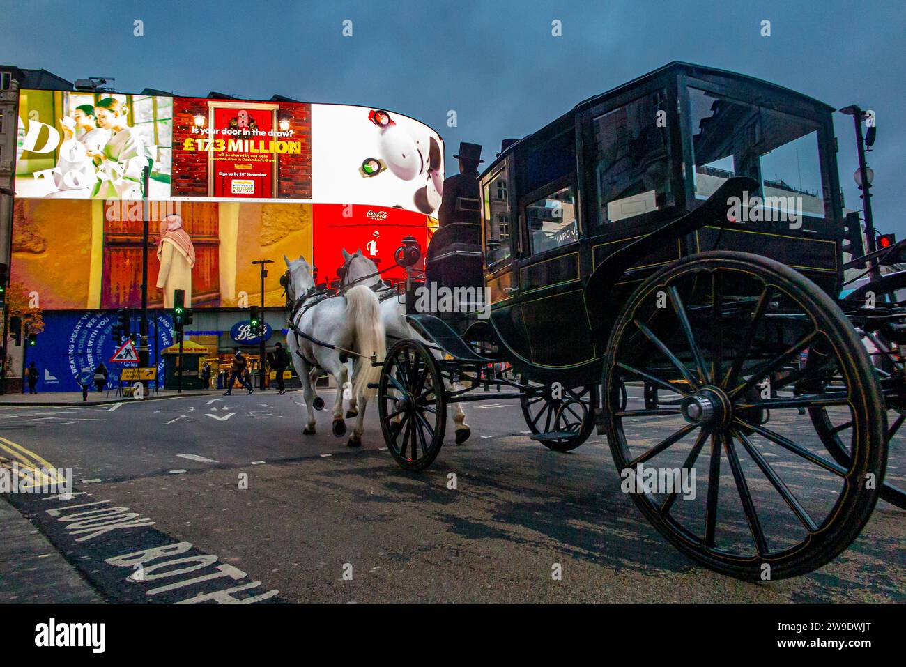An unusual sight as a horse drawn carriage trots through Piccadilly Circus early in the morning Stock Photo