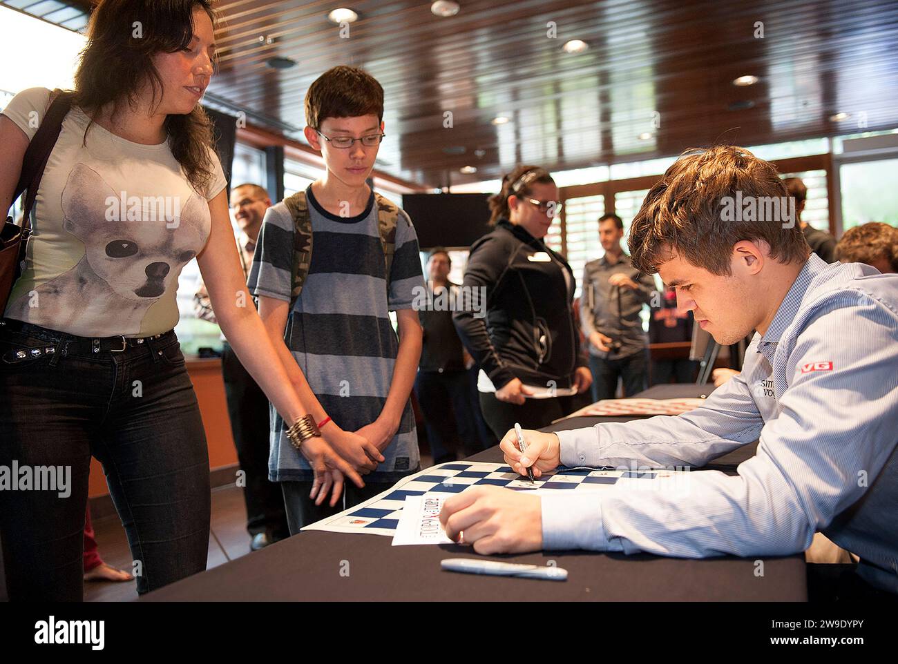 8 SEPT. 2013 -- ST. LOUIS -- Norwegian chess grandmaster Magnus Carlsen (right) signs autographs for Isaac Adams (center) and his mother Dora Jara, wh Stock Photo
