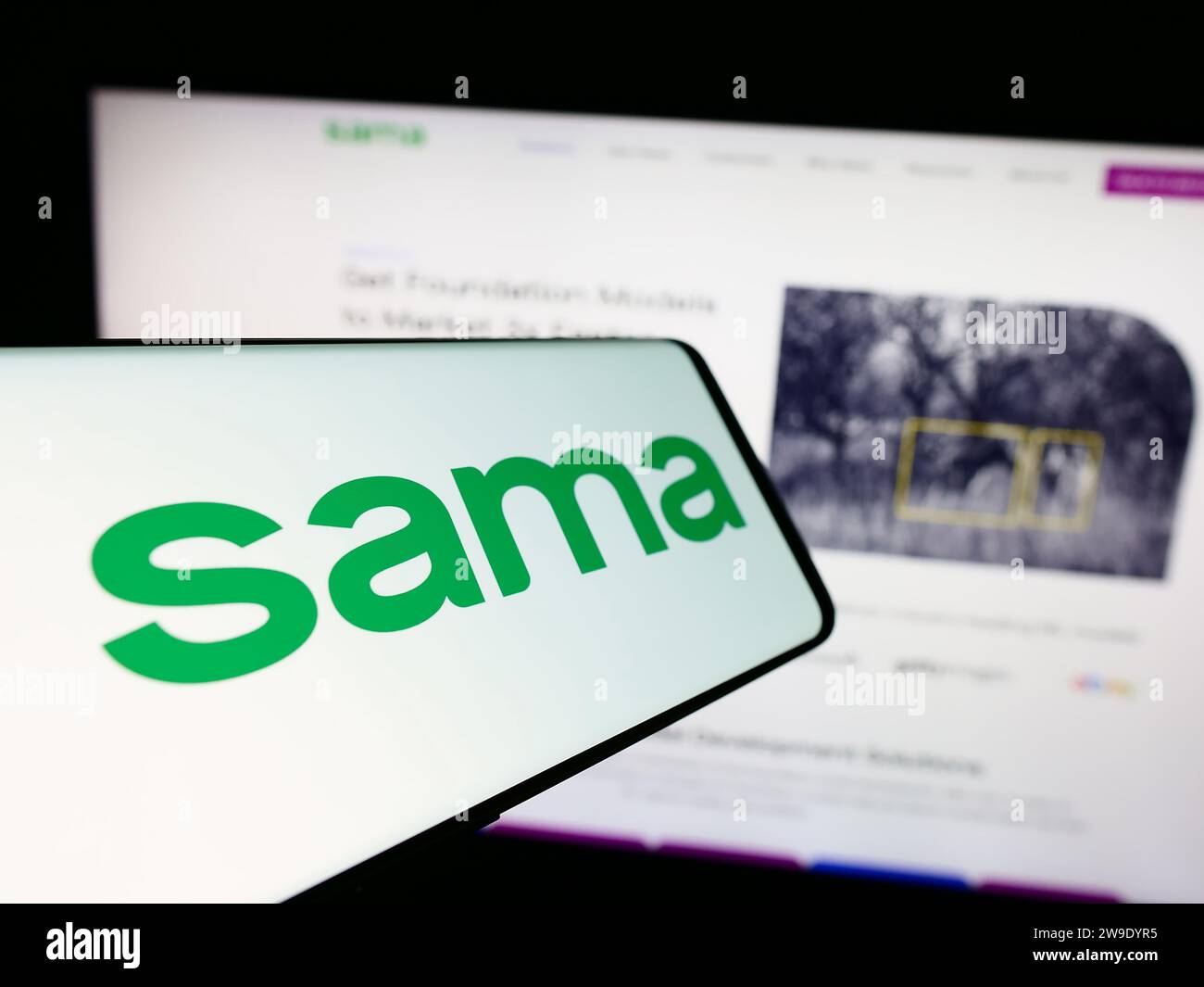 Smartphone with logo of American company Samasource Impact Sourcing Inc. (Sama) in front of website. Focus on center-left of phone display. Stock Photo