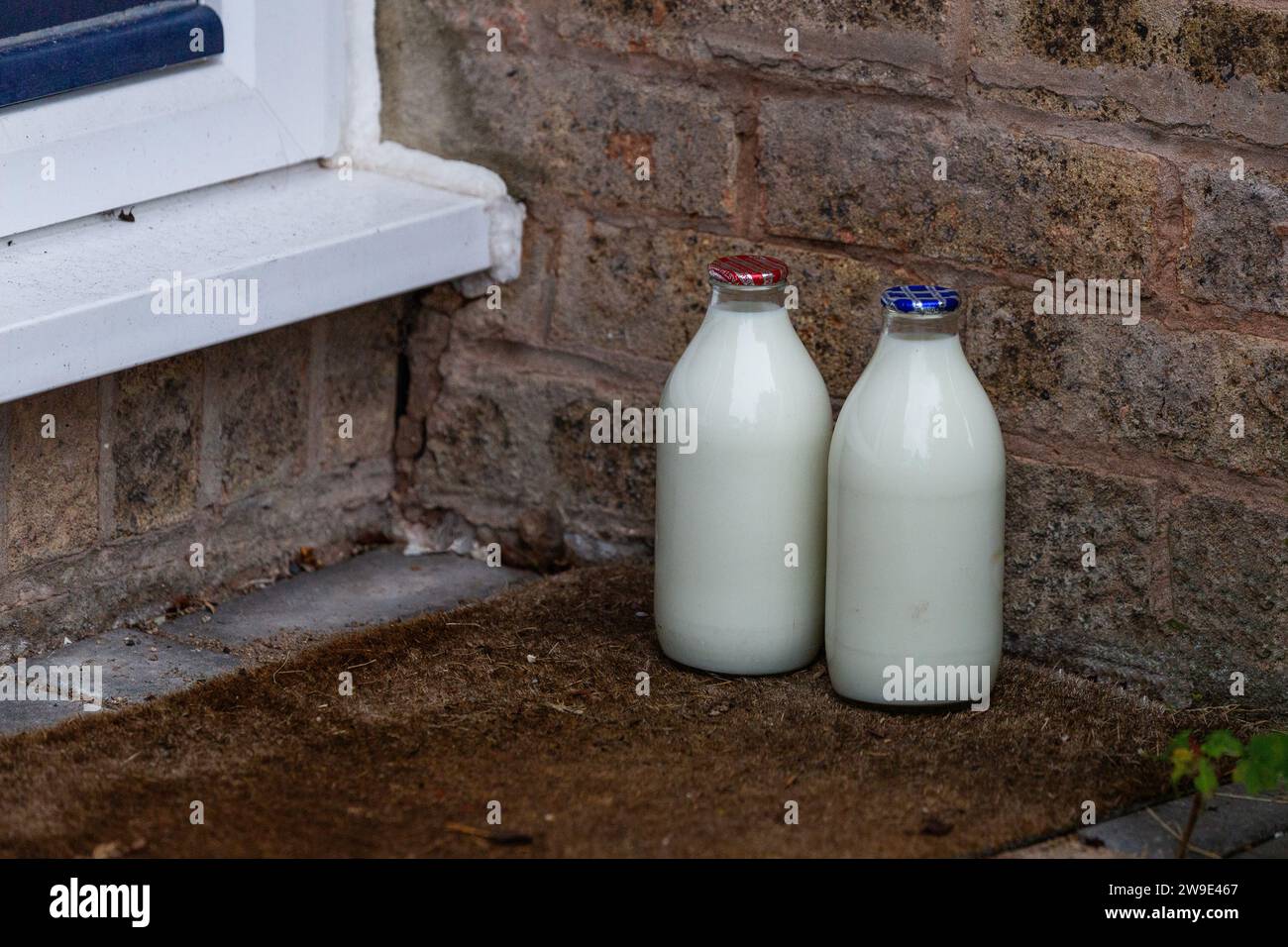 Doorstep milk delivery UK. A pint of skimmed milk and a pint of semi skimmed milk in glass bottles on a doorstep left by a milkman in the UK. Stock Photo