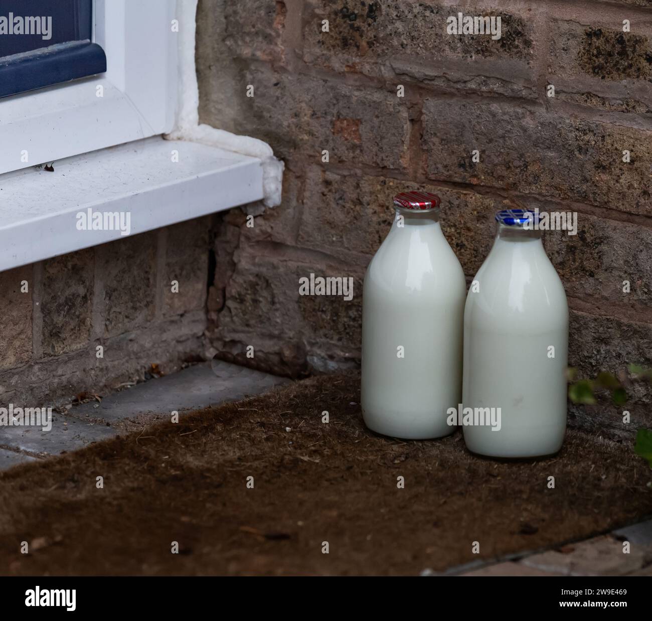 Doorstep milk delivery UK. A pint of skimmed milk and a pint of semi skimmed milk in glass bottles on a doorstep left by a milkman in the UK. Stock Photo