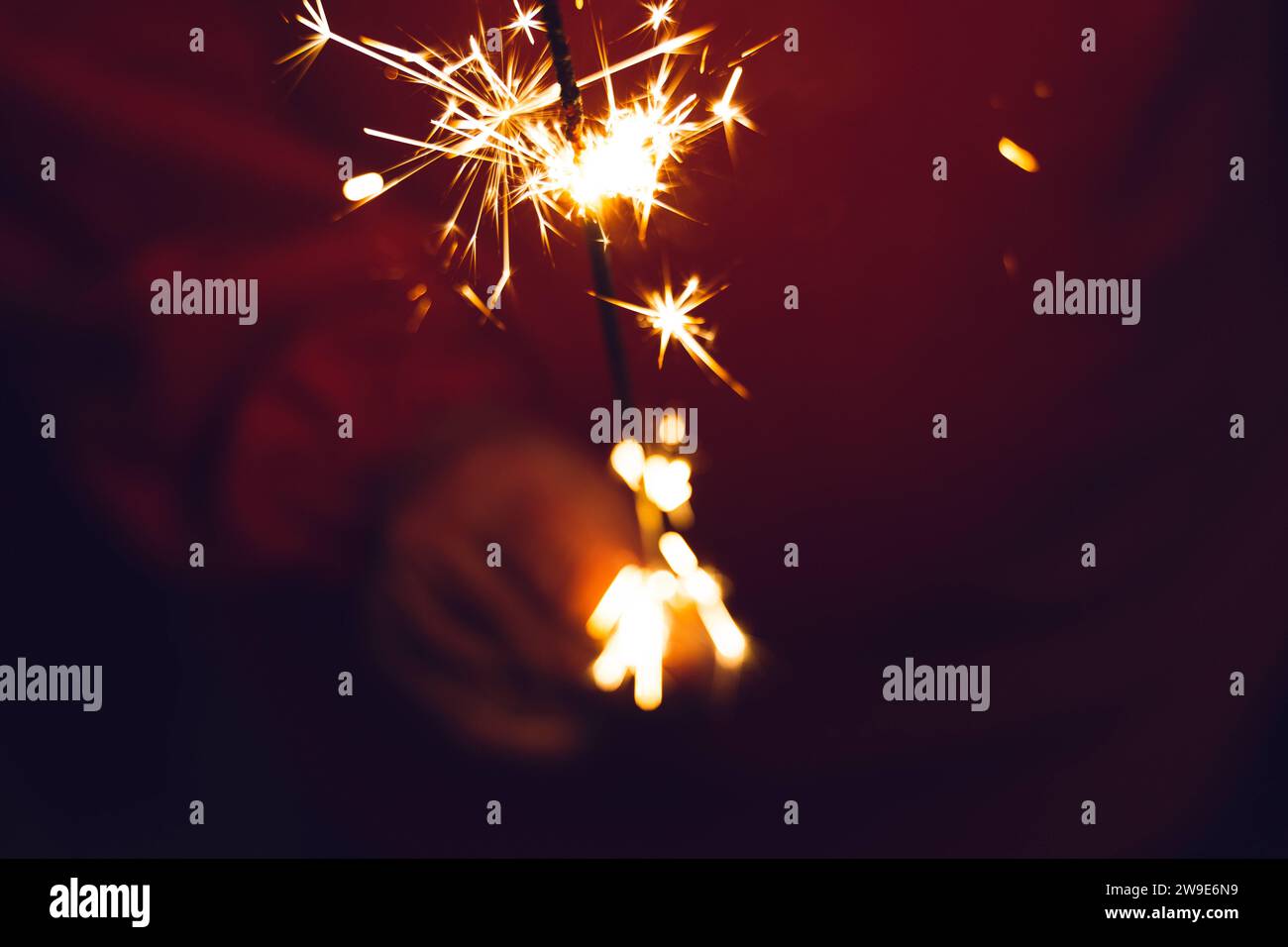 Kammlach, Bavaria, Germany - December 25, 2023: A woman holds a sparkler with bright sparks in her hand at night *** Eine Frau hält bei Nacht eine Wunderkerze mit hellen Funken in der Hand Stock Photo