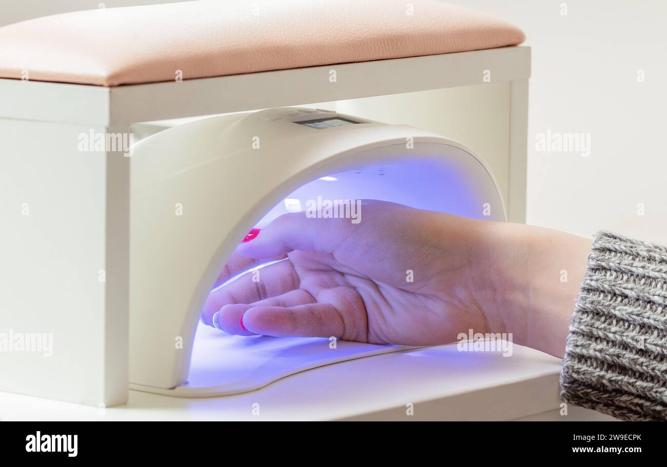 Woman's hand in UV lamp. Process of drying gel polish. Manicure process