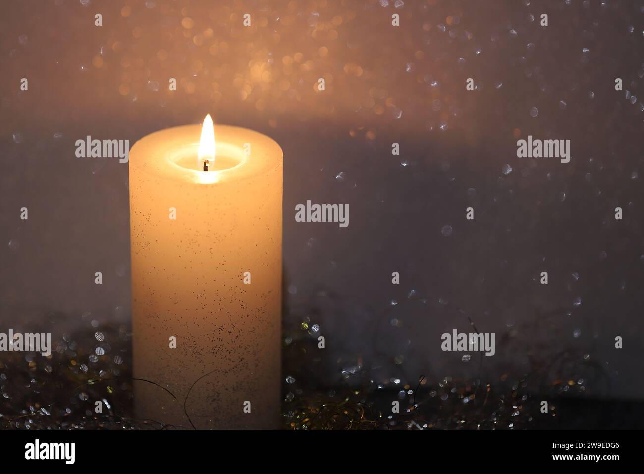 Close-up of a bright pillar candle against a black background, copy space Stock Photo