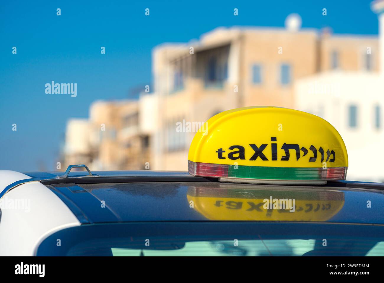Taxi in Israel. A Yellow tag on top of a vehicle featuring the word Taxi in English and Hebrew Stock Photo