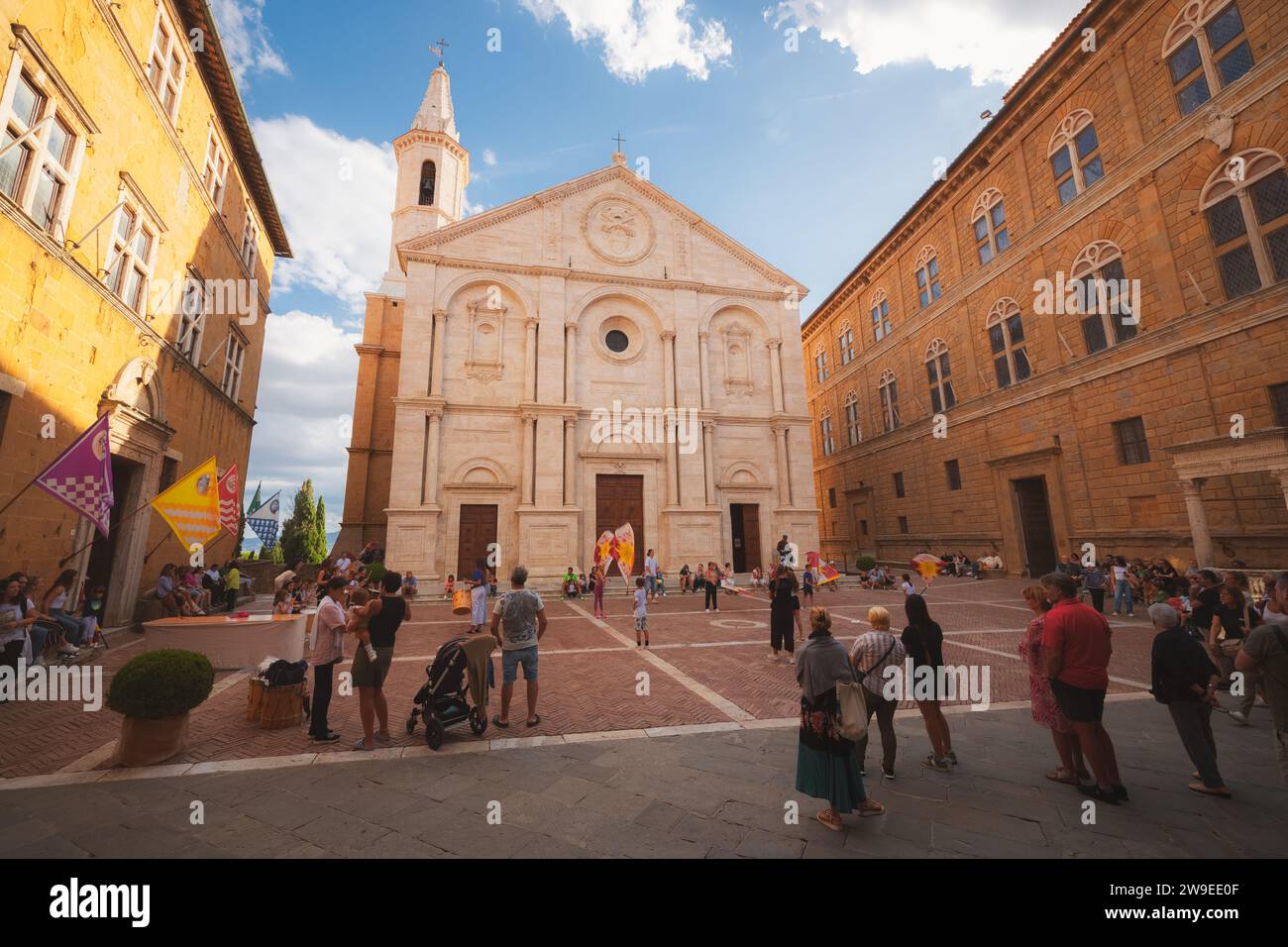 Pienza, Italy - August 31, 2023: Tourists and Italian locals enjoy the colourful, main old town square Piazza Pio II and Duomo di Santa Maria Assunta Stock Photo
