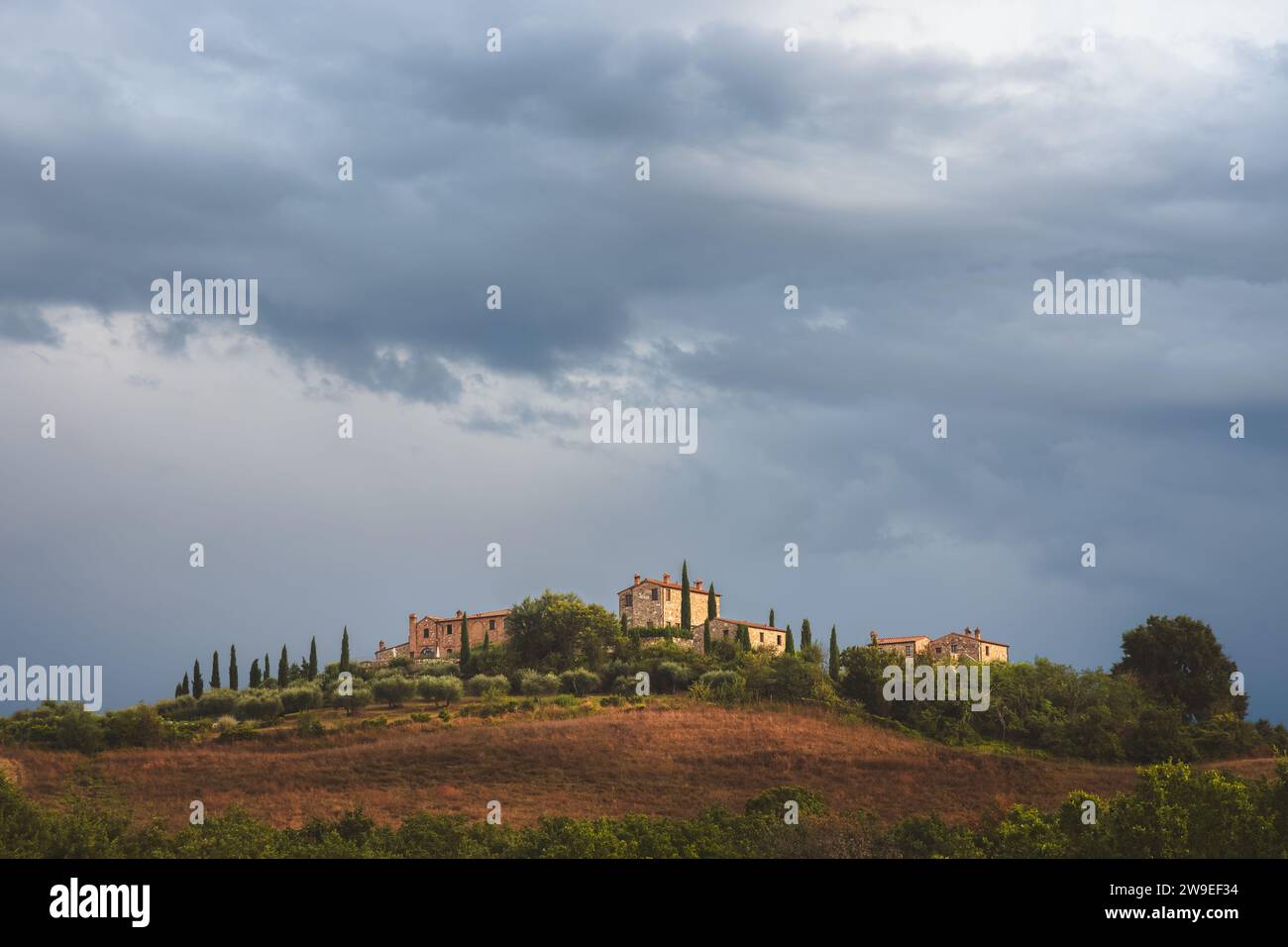 Moody, atmospheric light and dark dramatic sky over lone rustic stone farmhouse in the scenic countryside landscape of rolling hills and farmland of r Stock Photo