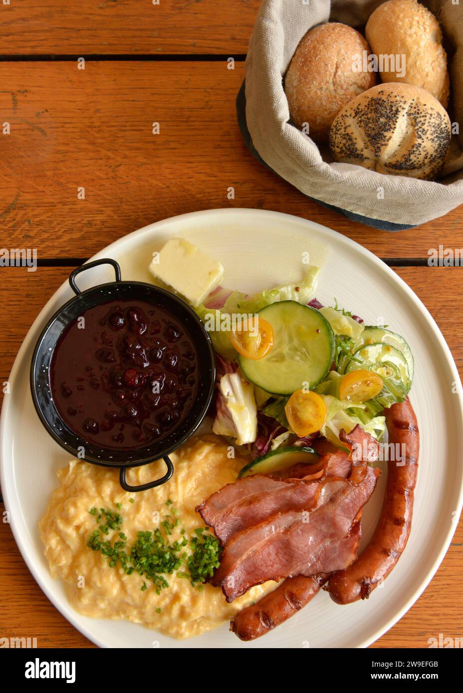 Traditional typical Polish breakfast consisting of bacon, sausages, scrambled eggs, fresh salad, jam and butter served in a restaurant in Poland, EU Stock Photo