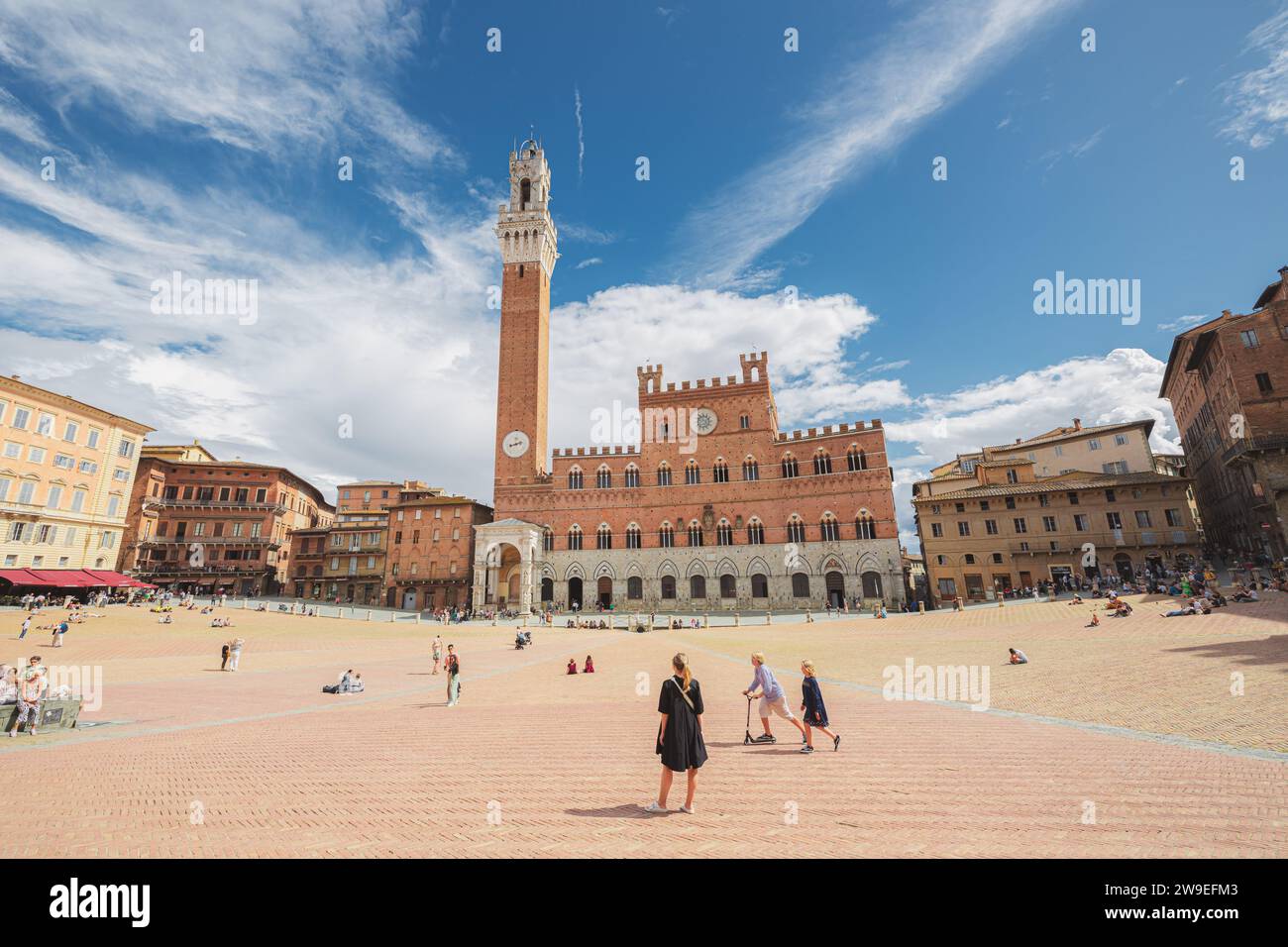 Siena, Italy - August 30, 2023: Tourists visit the main landmark and attraction Piazza del Campo with Palazzo Pubblico and its bell tower Torre del Ma Stock Photo